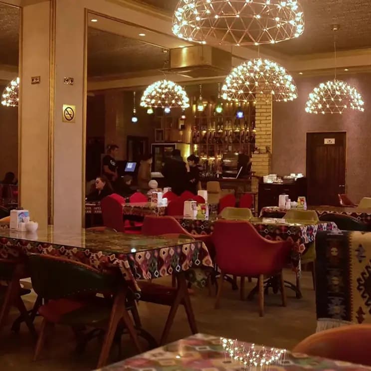 Уютный ресторан с барной стойкой, яркими светильниками и столами с разноцветными скатертями.