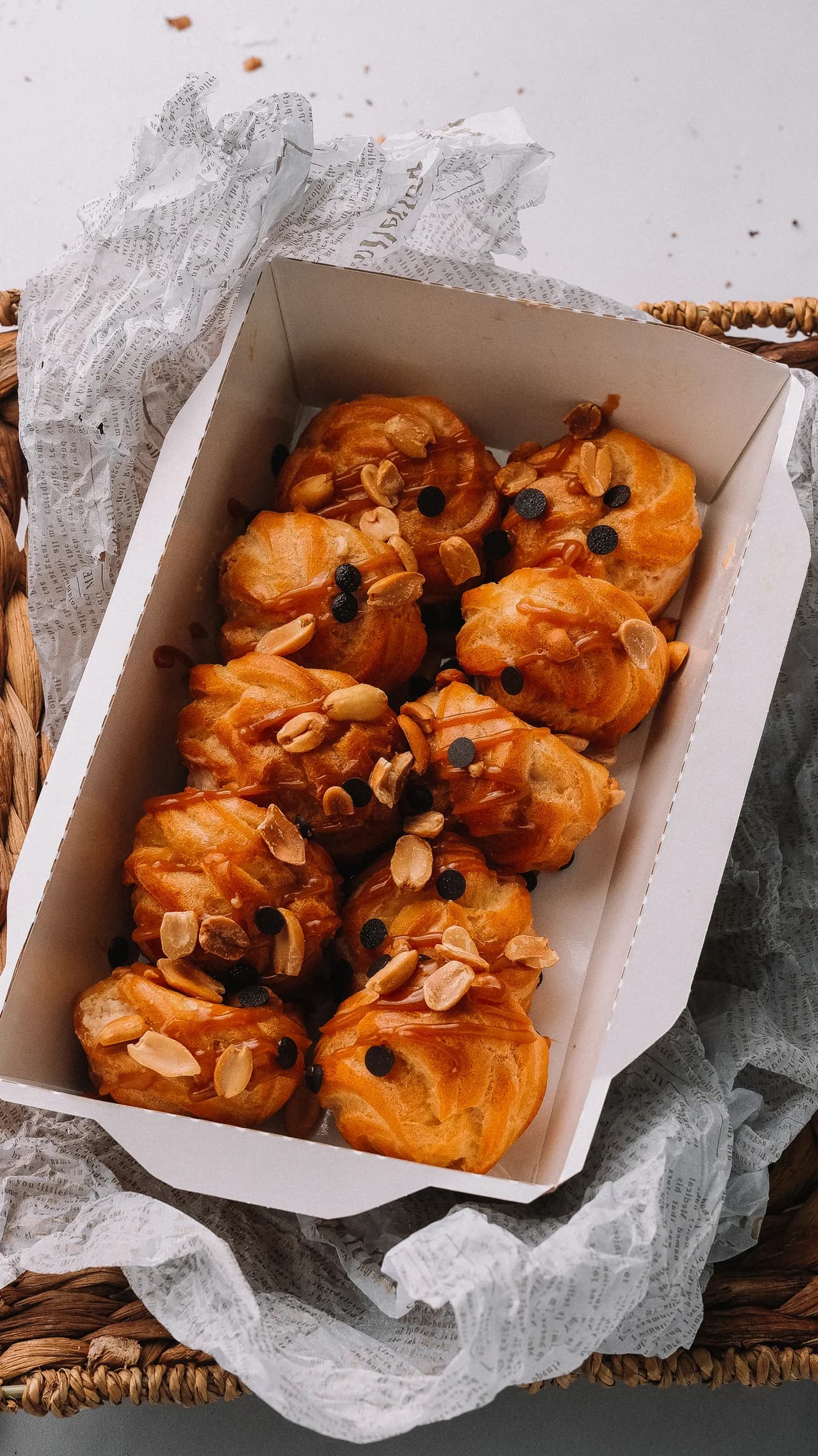 Коробка с профитролями, украшенными орехами и шоколадной крошкой.