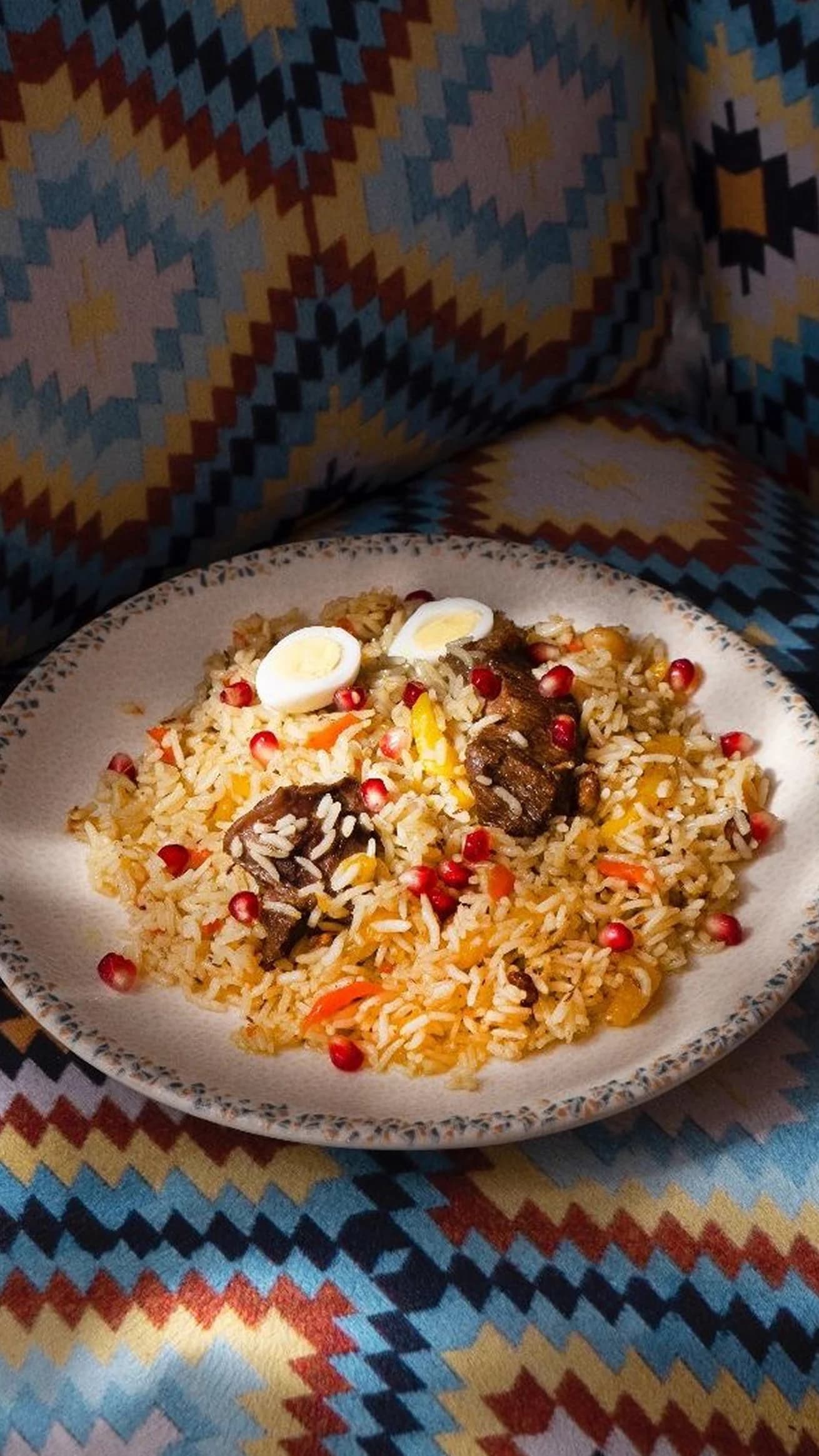 Тарелка узбекского плова с мясом, гранатом и перепелиными яйцами.